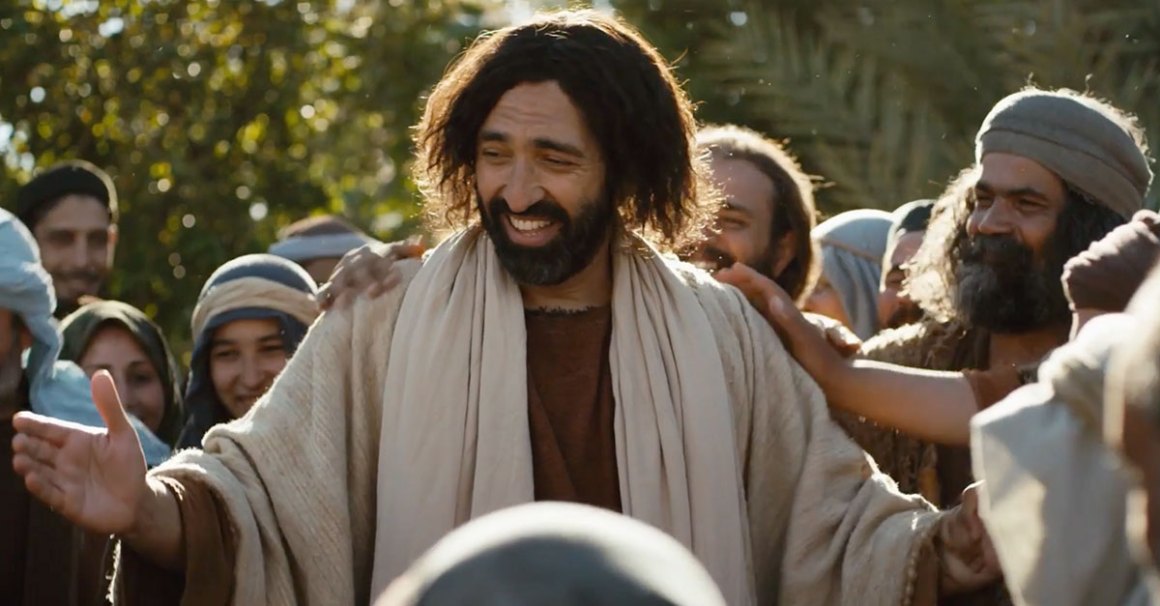 man is crowded by people while dressed in biblical era clothing