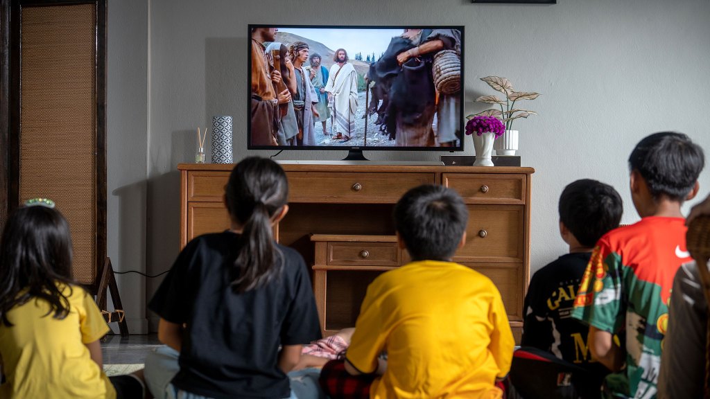Kids seated around a tv watching the Jesus Film