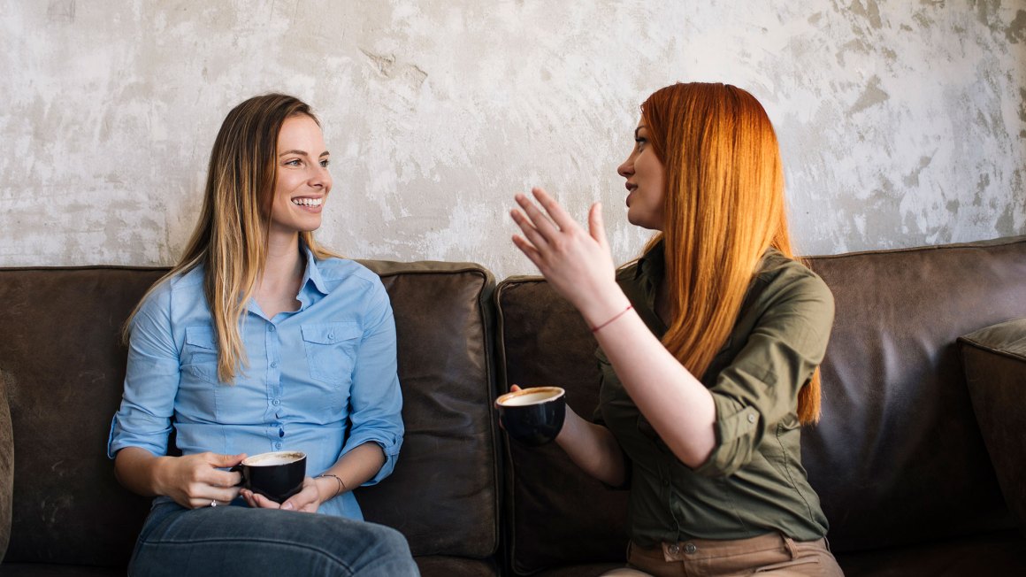 Two women sitting on a couch and talking