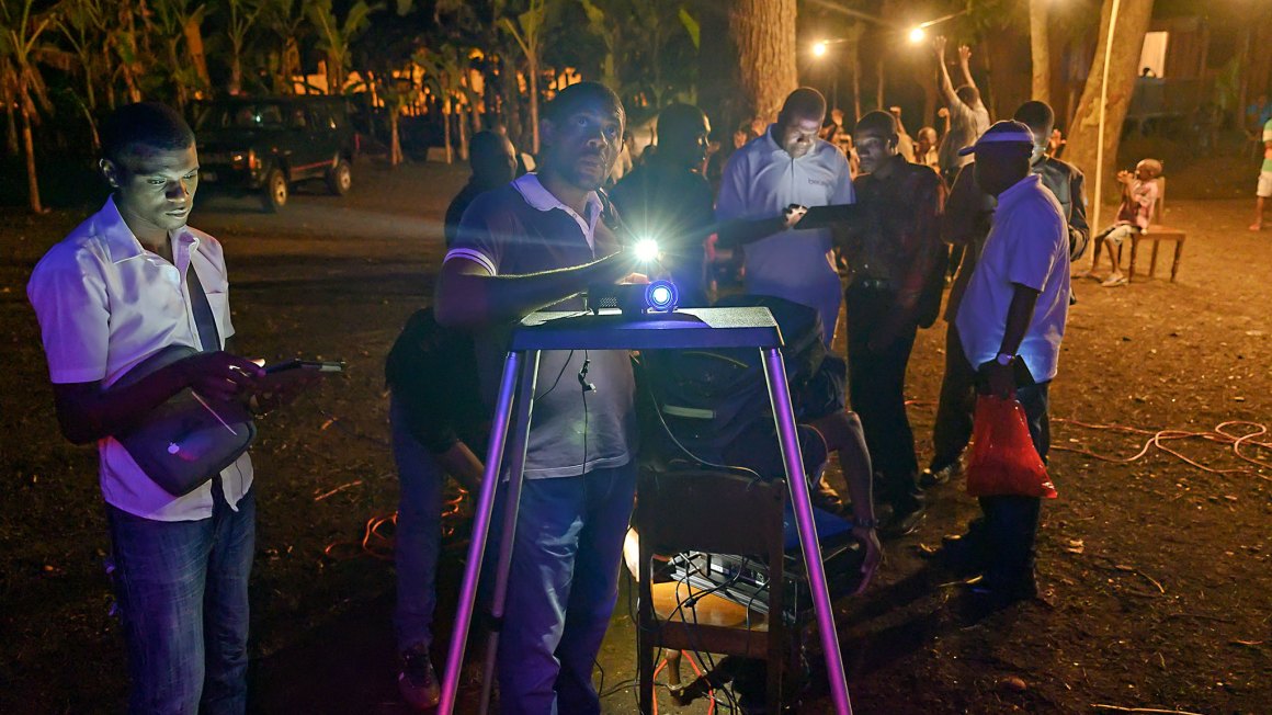 Men standing over projector