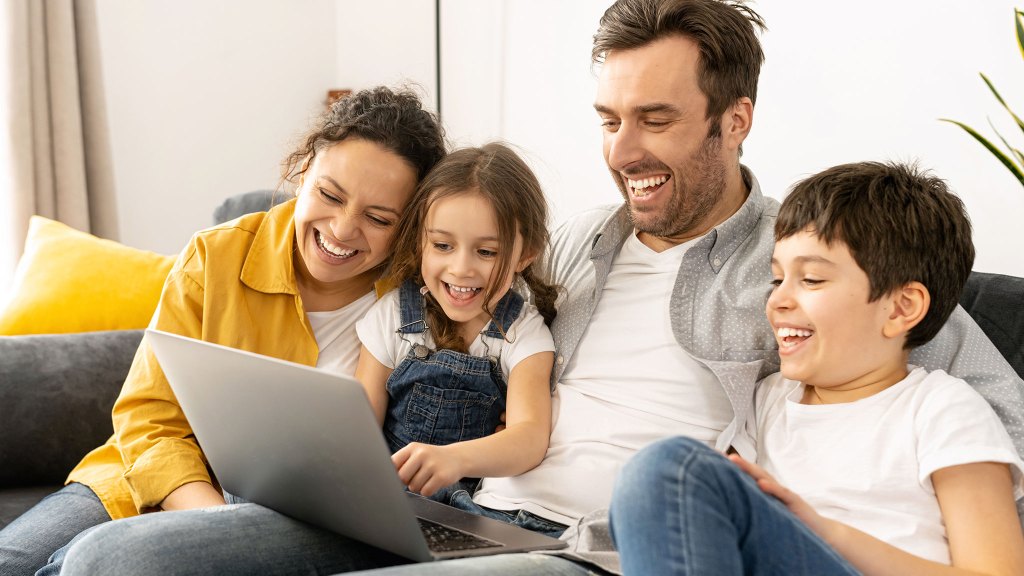 family sitting on couch looking at laptop