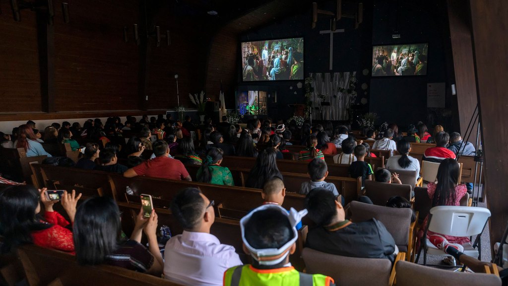 church full of people sitting and watching the Jesus FIlm on a projector
