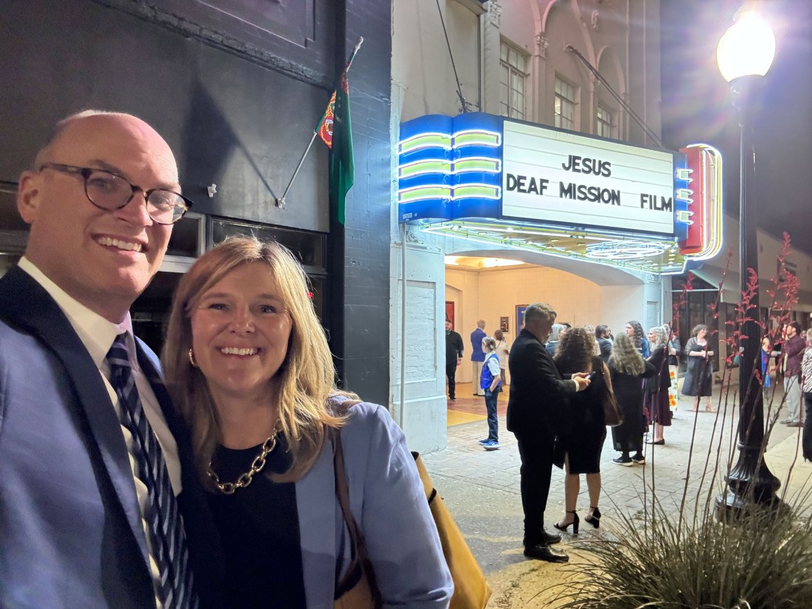 Holly and Josh newell standing in front of a movie theater with the sign JESUS DEAF MISSION FILM