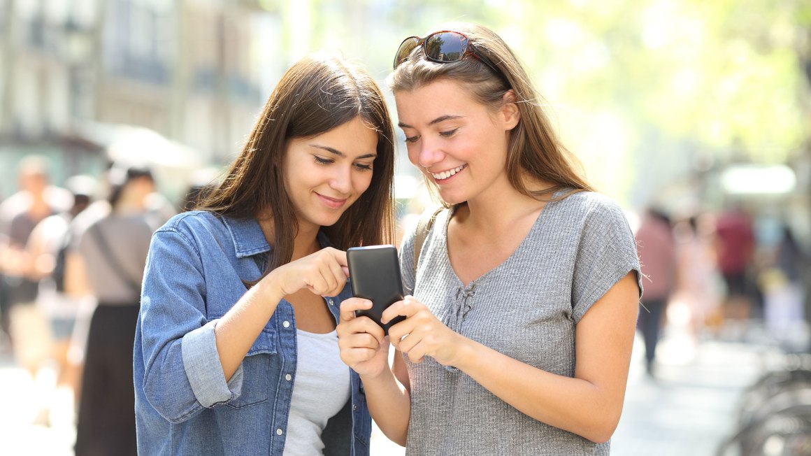 two woman looking at a cell phone