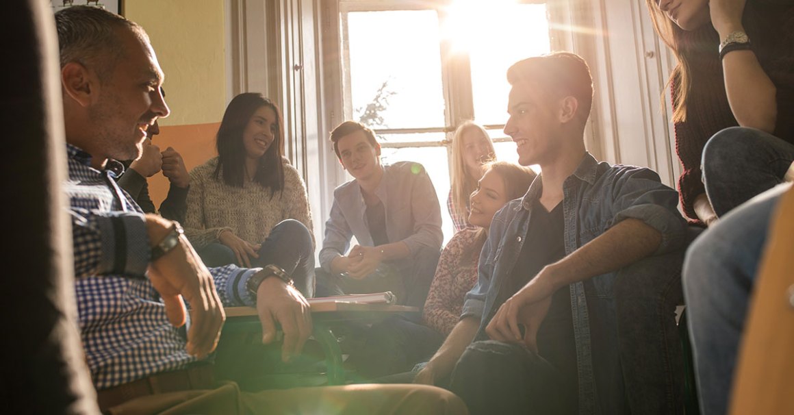 Two girls smiling and talking in a well-lit room, representing friendly connection and relationship-building in church evangelism