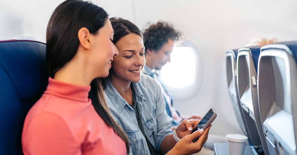 2 people on a plane looking at a phone