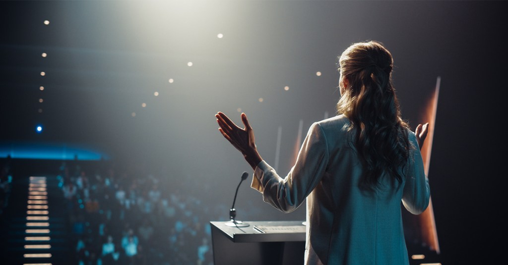 A woman at front of church evangelistic preaching to a group