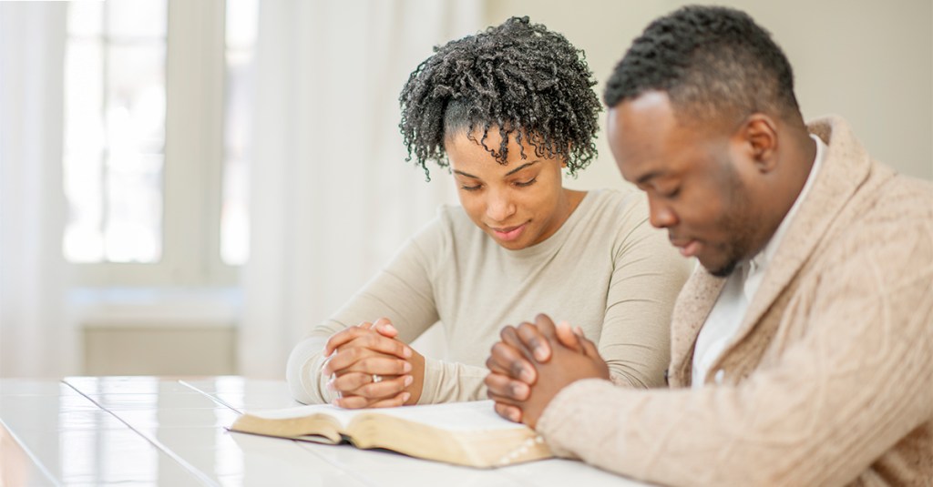 A man and a woman praying together over a Bible. Maybe asking to become a cheerful giver