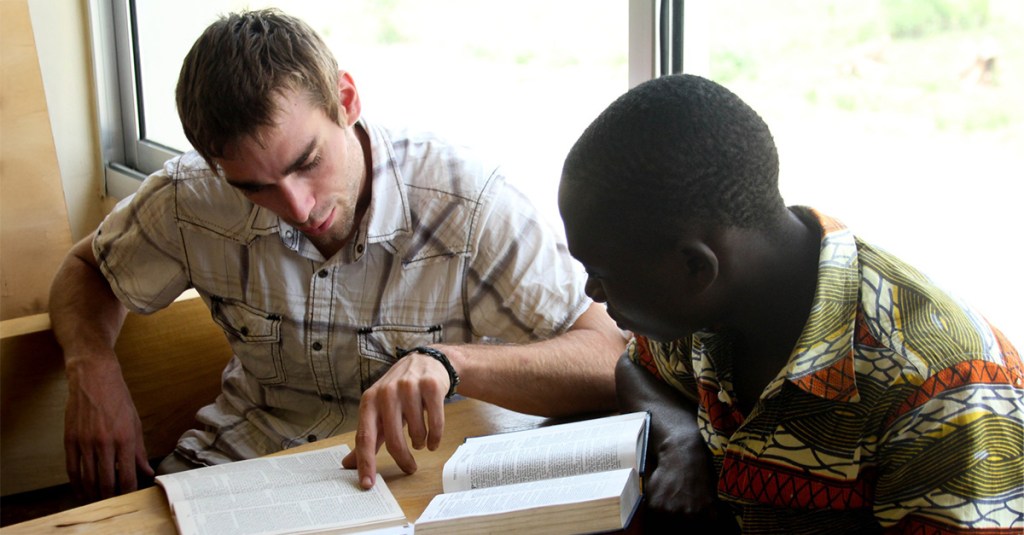 Two young me reading from Bibles. Answering the question of why evangelism is important.