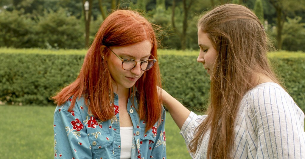 Two young women praying side by side. 